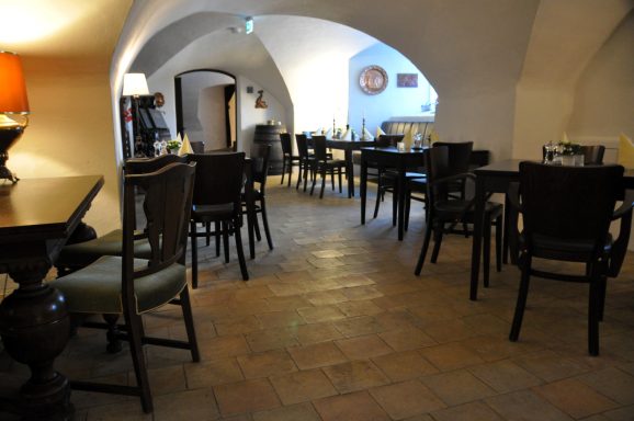 Gemütliches Restaurant mit Holztischen, Stühlen und einem gewölbten Deckenraum.